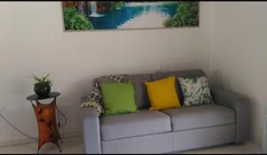 a couch with three colorful pillows sitting under a painting at Gîte Pousada Tropical in Volvent