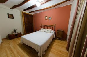 a bedroom with a white bed and orange walls at Casa Rural El Solanar in Castelserás