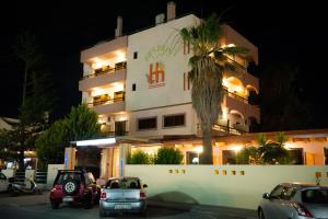 a building with cars parked in front of it at night at Heleni Beach Hotel in Ialyssos