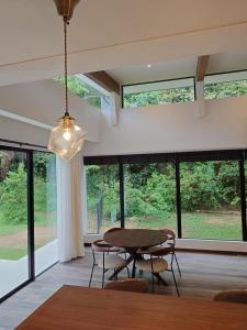 a dining room with a table and chairs and windows at VILLA Esse UNA in Nago