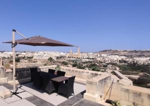 a patio with an umbrella and a table and chairs at Luxury apartment - Fort Chambray in Għajnsielem