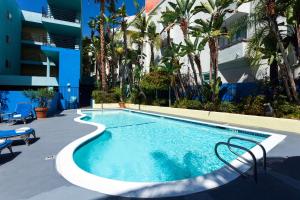 una piscina con sillas junto a un edificio en Ramada Plaza by Wyndham West Hollywood Hotel & Suites en Los Ángeles