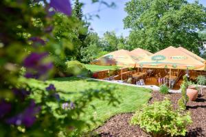 un jardín con sombrillas, mesas y flores en Guest House Bakhus, en Žerjavka