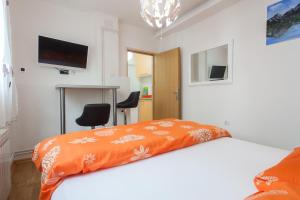 a bedroom with a bed with an orange blanket at Apartment Trešnja in Zagreb