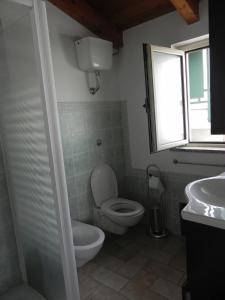 een badkamer met een toilet, een wastafel en een raam bij Panta House in San Giovanni Suèrgiu