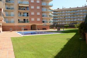 a building with a swimming pool next to a grass field at Brisa Beach in Santa Susanna