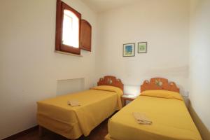 2 Betten in einem Zimmer mit gelber Bettwäsche und einem Fenster in der Unterkunft Scogliera del Gabbiano in Santa Maria di Leuca