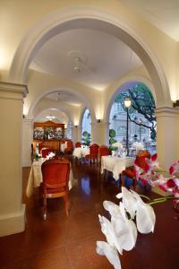 uma sala de jantar com mesas, cadeiras e flores em Hotel Continental Saigon em Cidade de Ho Chi Minh