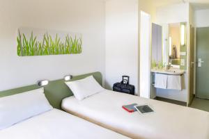 una camera d'albergo con due letti e un lavandino di ibis budget Koeln Porz a Colonia