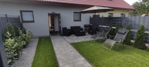 a patio with chairs and an umbrella in a backyard at Domek na Kaszubach nad jeziorem Kamień - Prywatne Jacuzzi i Rowerek Wodny in Kamień