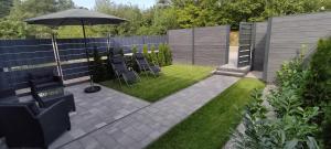 a patio with chairs and an umbrella in a backyard at Domek na Kaszubach nad jeziorem Kamień - Prywatne Jacuzzi i Rowerek Wodny in Kamień