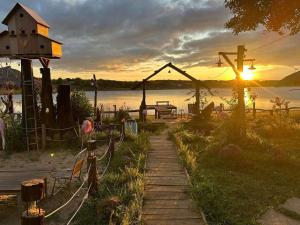 a sunset over a body of water with a wooden pathway at Biển Hồ Garden Glamping in Bien Ho