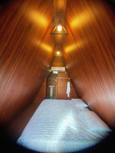 a bed in a room with a wooden wall at Biển Hồ Garden Glamping in Bien Ho