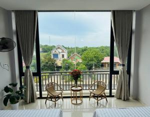 a bedroom with a large window with a table and chairs at Nhà Nghỉ Sukha in Ba Vì