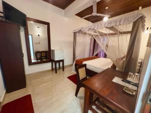 ein Schlafzimmer mit einem Bett, einem Tisch und einem Spiegel in der Unterkunft Nooit Gedacht Holiday Resort Unawatuna in Unawatuna