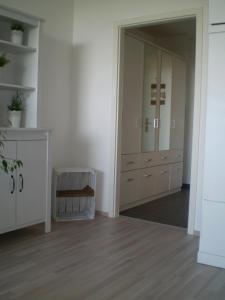 um quarto com armários brancos e um corredor com pisos de madeira em Ferienwohnung Marinablick em Wendtorf