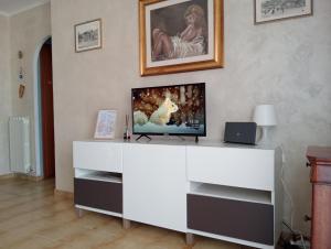 ネットゥーノにあるAppartamento Nettunoの白いエンターテイメントセンターの上に座ってテレビを見る