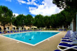 a swimming pool with blue lounge chairs and trees at La belle histoire in Montignac
