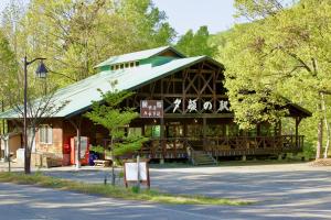 a large wooden building with a green roof at Yamanomura Campsite in Hida