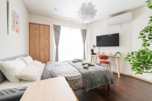 a bedroom with a bed and a couch and a tv at Oasis Stay Tokyo in Soka