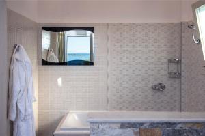 a bathroom with a tub and a sink and a mirror at Contaratos Beach Hotel in Naousa