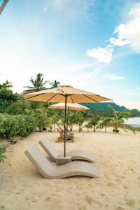 a beach with an umbrella and chairs on the sand at Bamboo Surf Beach in San Isidro