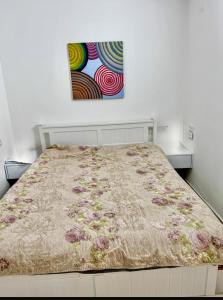 a bed in a bedroom with a painting on the wall at Villa Arviv in Ramat Yaẖanan +19 photos