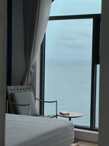 a bedroom with a bed and a table and a large window at Sunset Town Apartments Free Gym & Pool in Phu Quoc