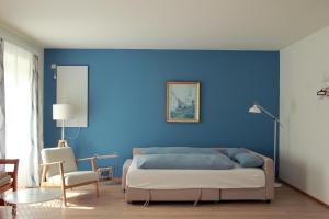 a bedroom with a blue wall with a bed and a chair at Wohnen im Meierhof in Hohenwarth