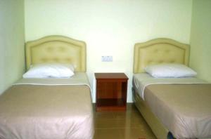 duas camas sentadas uma ao lado da outra num quarto em Ten Inn em Kuala Terengganu