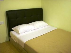 - un lit avec une tête de lit noire et 2 oreillers blancs dans l'établissement Ten Inn, à Kuala Terengganu