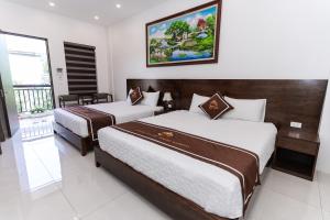 a hotel room with two beds and a picture on the wall at Tam Coc Morning Homestay & Spa Ninh Binh in Vũ Lâm