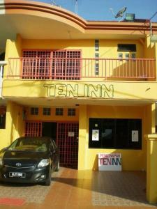 a car parked in front of a yellow building at Ten Inn in Kuala Terengganu
