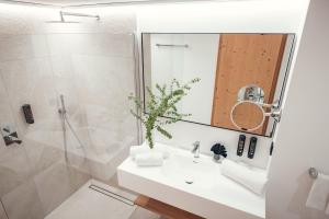 a bathroom with a sink and a shower and a mirror at Ganischgerhof Mountain Resort & Spa in Nova Ponente