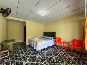 a bedroom with a bed and two red chairs at Abadi Guest House Tuktuk in Tuktuk Siadong