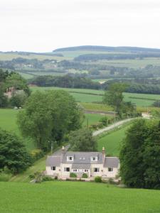 ein großes weißes Haus auf einem grünen Feld in der Unterkunft Eastwood Cottage in Turriff