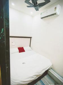 a bedroom with a white bed with a red pillow at royal guest house and dormitory in asalpha in Mumbai