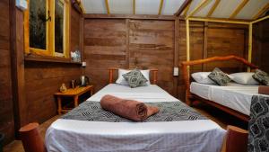 two beds in a room with wooden walls at Farming Tree House in Sigiriya