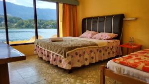 a bedroom with a bed with a view of the water at Abadi Guest House Tuktuk in Tuk Tuk