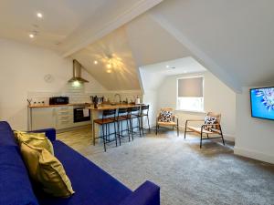 Una sala de estar con un sofá azul y una cocina. en Roath - Modern Flat Near City Centre WParking Pass the Keys, en Cardiff