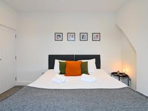 1 dormitorio con 1 cama grande con almohadas de color naranja y verde en Roath - Modern Flat Near City Centre WParking Pass the Keys, en Cardiff