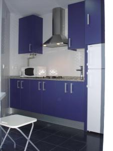 cocina con armarios azules y nevera blanca en Apartamento Cantabrico, en Cádiz