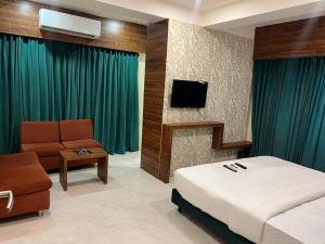 a bedroom with a bed and a chair and a television at Hotel Enigma in Indore