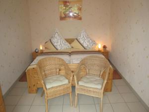 a bedroom with a bed with two wicker chairs at Vineyard View Romantic Stay in Kinheim