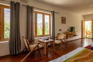 una camera da letto con tavolo, sedie e finestre di Hotel Karma Inn, Nubra Valley, Leh, Ladakh a Hundar