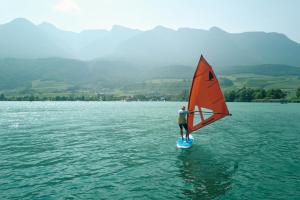a man on a sail board in the water at Leuchtenburg am See in Caldaro