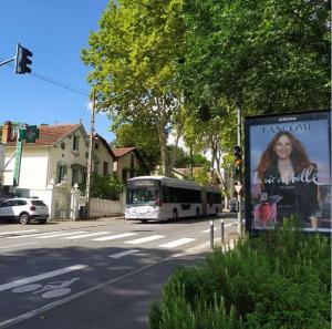 a bus driving down a street with a billboard at Charme et jardin in Toulouse