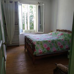a bedroom with a bed with a floral comforter and a window at Charme et jardin in Toulouse +9 photos