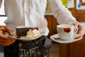 a man holding a piece of cake and a cup of coffee at Gasthof Speneder in Altpölla +37 photos