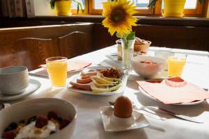 a table with breakfast foods and orange juice and a sunflower at Gasthof Speneder in Altpölla